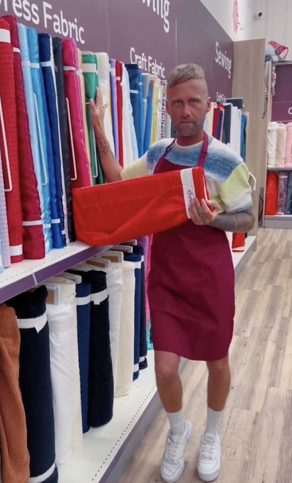 Screenshot Hobbycraft uses employee-generated content (EGC) in this screenshot of a TikTok video with an employee in the fabric aisle of their store holding a reel of red fabric.